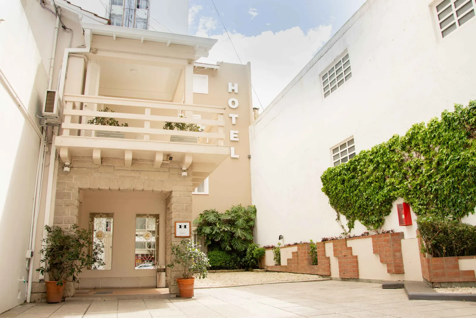 Ingreso al hotel con balcones blancos y plantas
